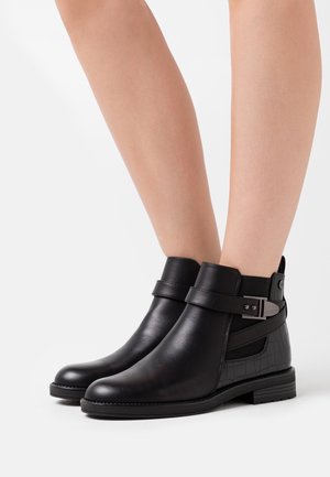 Bottines noires en cuir lisse, avec un côté texturé en motif crocodile et un accent de boucle. Conception à bout rond et talon bas.