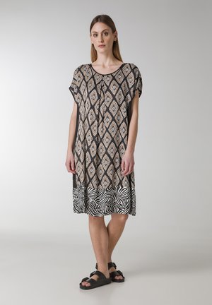 Abito a maniche corte con un motivo geometrico a rombi nei colori marrone, bianco e nero, con orlo a strisce zebra e vestibilità rilassata.
