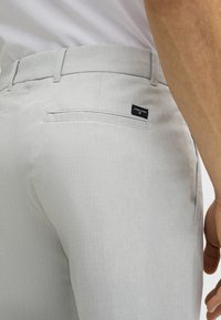 Pantaloni grigi chiari con una finitura testurizzata, dotati di una tasca posteriore con un'etichetta nera e un design slim-fit.