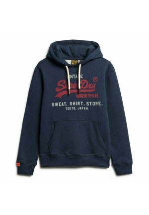 Marineblå hættetrøje med justerbar snor, frontlomme og trykt tekst: "Vintage SuperDry" med detaljer fra Tokyo Japan og cremefarvede accenter.
