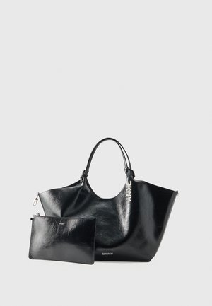 Sac cabas DKNY en cuir noir avec doubles anses, accompagné d’une pochette plate assortie à fermeture éclair, les deux avec des détails argentés de la marque.