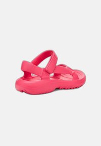 Rosa sandaler med justerbara remmar, en strukturerad fotbädd och en flexibel gummisula som är designad för komfort och grepp.