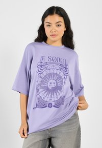 Lavender oversized t-shirt with a round neck, featuring a purple sun graphic and astrology symbols. Made from soft cotton fabric.