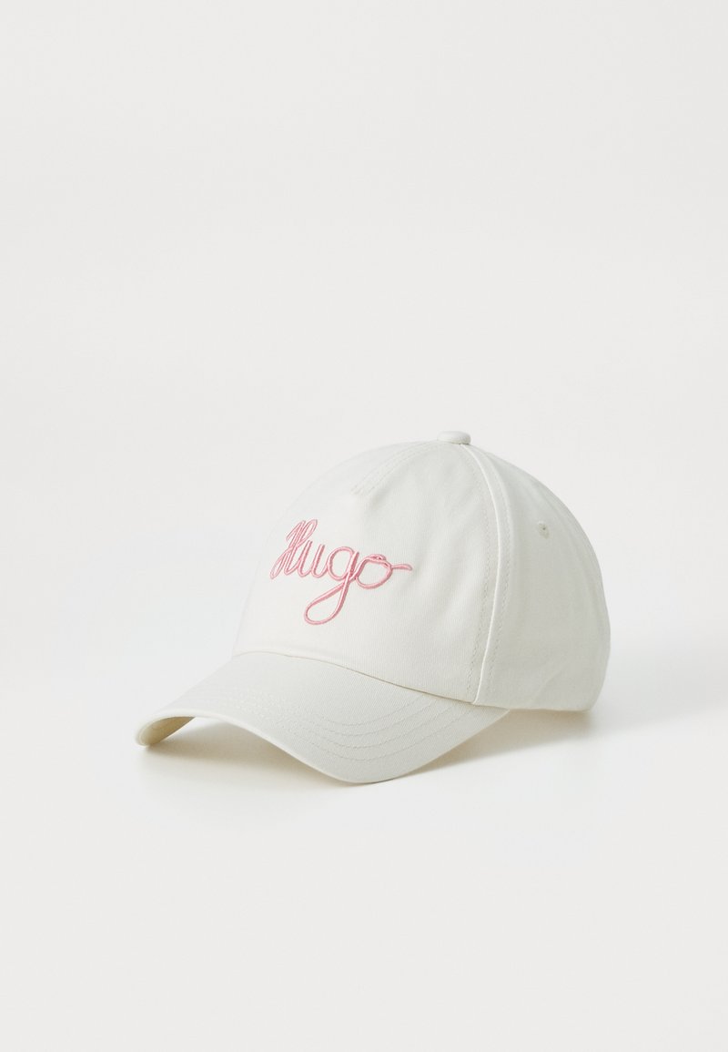 Valkoinen baseball-hattu, joka on valmistettu puuvillasta ja jossa on vaaleanpunainen kirjailtu "Hugo"-logo edessä. Säädettävä hihna takana. Rennon tyylinen muotoilu.