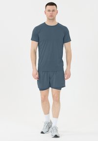 Harmaa urheilupaita ja siihen yhdistelevät shortsit kevyestä, kosteutta siirtävästä kankaasta. Mukana pyöreä kaula-aukko ja virtaviivainen muotoilu mukavuuden takaamiseksi.