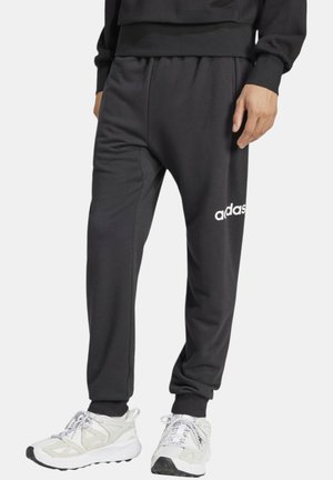 Pantaloni della tuta neri con una vestibilità comoda, dotati di un cintura elasticizzata e un accento logo bianco. Tessuto morbido, gambe dritte e caviglie polsino.