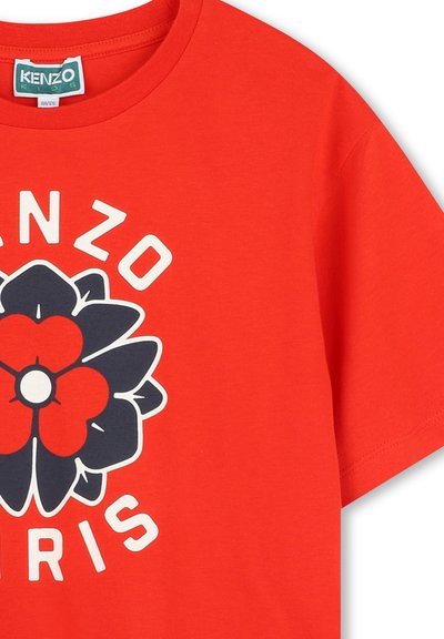 T-shirt en coton rouge avec un grand motif floral noir et rouge, et le texte "KENZO PARIS" en blanc, col rond et manches courtes.
