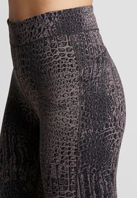 Krótkie legginsy z wysokim stanem, z teksturowanym czarno-brązowym wzorem węża i płaskimi szwami dla wygody.