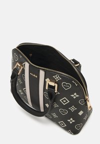 Sac à main structuré avec un motif noir et blanc présentant des cœurs et des formes géométriques. Comprend une fermeture éclair dorée et deux poignées en cuir.