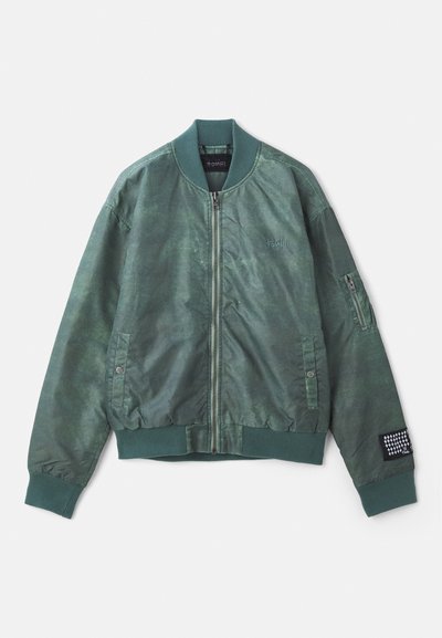 Roheline bomber-jakk tekstuuriga kangast, millel on ees lukk, ribitud krae ja küljekotid. Vasakul varrukal on lukuga tasku.