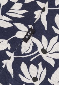 Marine stoffen met grote witte bloemmotieven en zwarte centra; bevat een klein zwart label met "J&Joy." Zacht van textuur en een casual ontwerp.