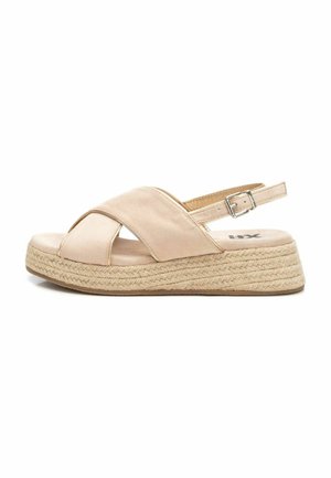 Sandalia espadrille beige con un diseño entrecruzado, parte superior de tela suave, correa ajustable en el tobillo y suela de plataforma de yute trenzado.