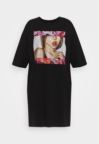 Czarny, luźny t-shirt z kolorowym nadrukiem przedstawiającym kobietę trzymającą lizaka. Krótkie rękawy i okrągły dekolt.