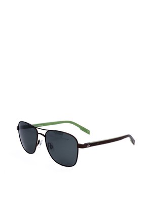 Occhiali da sole con lenti quadrate nere, sottilissima montatura metallica marrone e aste in plastica verde con naselli su sfondo bianco.