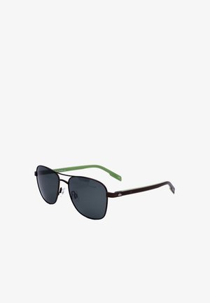 Occhiali da sole con lenti quadrate nere, sottilissima montatura metallica marrone e aste in plastica verde con naselli su sfondo bianco.