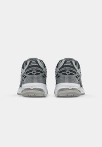 Gray running shoes with mesh upper, white midsole, and textured outsole. Features branding at the heel and a cushioned collar for comfort.