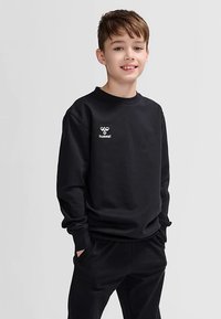 Svart sweatshirt med rund halsringning, ledig passform, ribbade muddar och broderad vit logotyp på bröstet, matchad med svarta byxor.