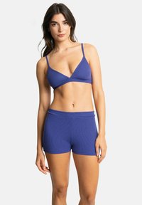 Bralette violet à côtes avec des bretelles fines et un short taille haute assorti. Le tissu semble doux et lisse, avec un design ajusté.