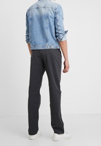 Džínová bunda v světle modré barvě s krátkým střihem, kombinovaná s tmavě šedými kalhotami a bílými teniskami. Bunda má vyhrnuté rukávy a kovové knoflíky.