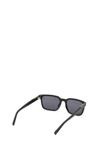 Occhiali da sole rettangolari neri con lenti scure, finitura opaca testurizzata, dettagli metallici sulle aste e aste sottili e diritte.