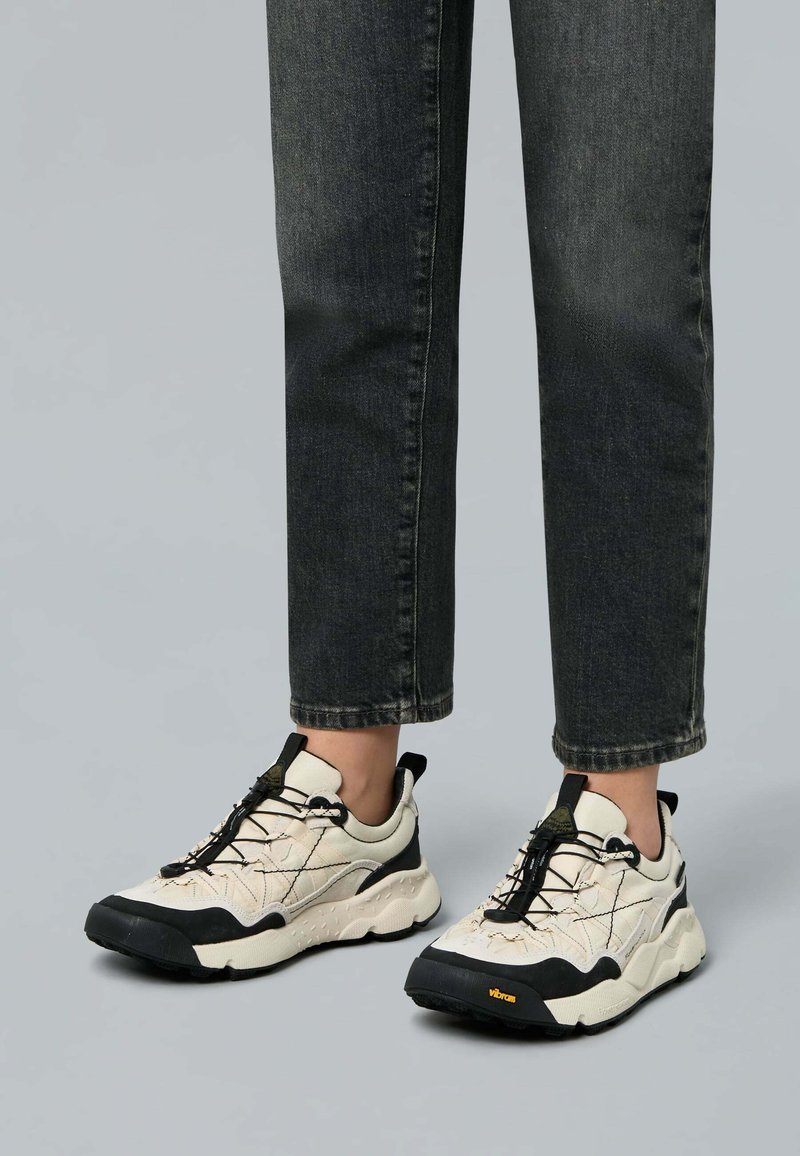 Sneakers chunky con una combinazione di colori crema e nero, caratterizzati da una tomaia testurizzata, suola in gomma nera e lacci elastici per una vestibilità sicura.