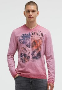 Long-sleeve, pink cotton T-shirt featuring a graphic print with text reading "THE SEVEN SUMMITS." V-neck design and casual fit.