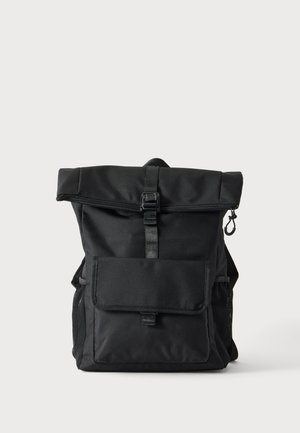 Zwarte rolltop rugzak met voorflapzak, gespsluiting, zijmeshvakjes en een haak aan de rechterkant tegen een effen achtergrond.