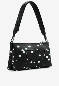 Borsa in tessuto nero con design intrecciato, caratterizzata da pois bianchi. Spallaccio regolabile e chiusura con zip. Texture liscia e forma elegante.