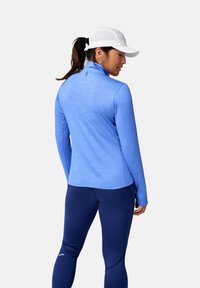 Vaaleansininen urheilullinen pitkähiha, jossa on korkea kaulus, pehmeä kangas ja kapea malli, yhdistetty tummansinisiin leggingsseihin, joissa on ompeluyksityiskohtia.