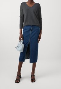 Pull gris à col en V avec manches 3/4, associé à une jupe midi en denim avec une fente avant. Sandales noires à talons et sac à main bleu clair complètent le look.
