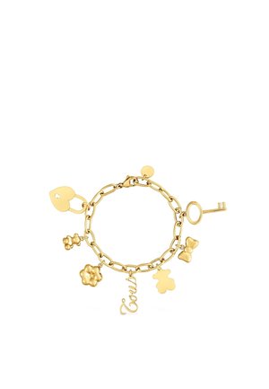 Bracciale con catena in oro con ciondoli che includono un lucchetto a forma di cuore, una chiave, un orsacchiotto, un fiocco, un fiore e il nome "Tous" scritto in corsivo.