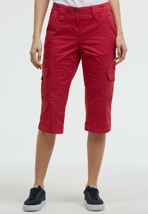 Rote knielange Cargoshorts, getragen mit weißem Hemd und schwarzen Sneakern auf hellem Hintergrund.