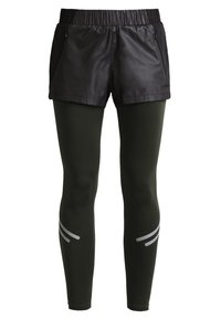 Svarta vattentäta shorts lager över mörkgröna leggings, med reflexer och ett elastiskt midjeband för komfort.