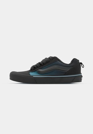 Zwarte en teal sneaker met een synthetisch bovenwerk, textuurafwerking, platte rubberen zool en vetersluiting. Bevat blauwe accenten en een verstevigde hiel.
