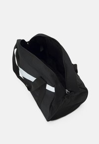 Black duffel bag with a gray horizontal stripe, made of durable fabric, featuring a zip closure and sturdy handles. Interior is spacious.