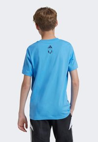 Camiseta de algodón azul con mangas cortas, que presenta un diseño de logo negro en la parte superior de la espalda. Corte relajado con una textura suave.