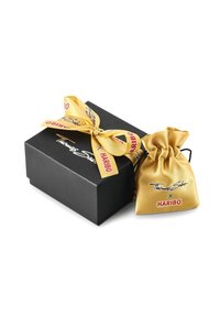 Must mustrakk must, kus on kuldne satiinist tõmblukk. Tõmbluku peal on trükitud "Thomas Sabo x HARIBO". Kast on seotud ribaga, millel on logod.