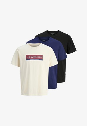 Three crew-neck t-shirts: one cream with graphic print, one navy, and one black. Made of cotton, short sleeves, and a relaxed fit.