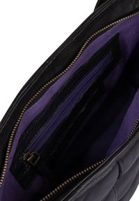 Zwarte leren handtas interieur met een paarse voering, twee ritszakken en meerdere pasjeshouders. Gouden ritsdetails zichtbaar.