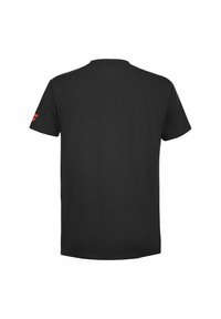Camiseta de algodón negra con cuello redondo, mangas cortas y un detalle del logo rojo en la manga izquierda, que muestra un diseño simple y un color sólido.