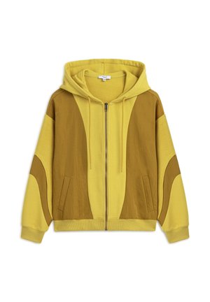 Felpa gialla con zip, realizzata con una combinazione di tessuti testurizzati e decorata con motivi astratti marroni, con tasca a marsupio e cappuccio regolabile con cordino.