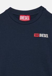 Μπλε βαμβακερό t-shirt ναυτικού στυλ με στρογγυλή λαιμόκοψη. Διαθέτει μικρό κόκκινο λογότυπο 'DIESEL' τυπωμένο σε λευκό και κόκκινο στην αριστερή πλευρά του στήθους.