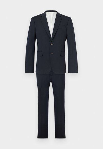 Κουστούμι ναυτικού μπλε με δύο κουμπιά, πέτο με σχισμή και ταιριαστό παντελόνι με ίσια μπάτζα, σε λευκό φόντο.