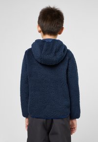 Sweat à capuche en polaire bleu marine avec un extérieur texturé et en peluche et un design simple. Il dispose d'une capuche et de manches longues, avec un ourlet arrondi.