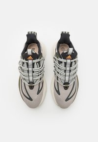 Para szarych i czarnych butów do biegania Adidas z jasnoszarymi sznurówkami ułożonymi w wzór przypominający sieć, widziane z góry na białym tle.