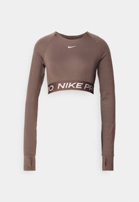 Langärmliges braunes Nike Pro Sportoberteil, cropped, mit Daumenlöchern und Logo-Band an der Taille auf weißem Hintergrund.