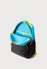 Μπλε και μαύρο σακίδιο με φερμουάρ και λαβή σε νέον πράσινο χρώμα, το κύριο διαμέρισμα ανοιχτό που δείχνει εσωτερική τσέπη και πλαϊνή δίχτυ θήκη.