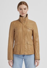 Braune Lederjacke mit hohem Kragen, zwei Brusttaschen und Seitentaschen. Glatte Textur, taillierter Schnitt und Druckknopfdetails.