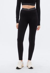 Μαύρο κολάν με εφαρμοστή σχεδίαση και ελαστική ζώνη μέσης με το λογότυπο "TOMMY JEANS". Μαλακό ύφασμα με λεία υφή.