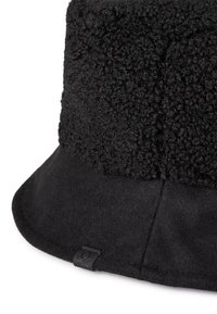 Černý kšiltovka s texturovanou, měkkou vrchní částí a hladkým, plstěným okrajem. Obsahuje malou značkovou etiketu po straně.